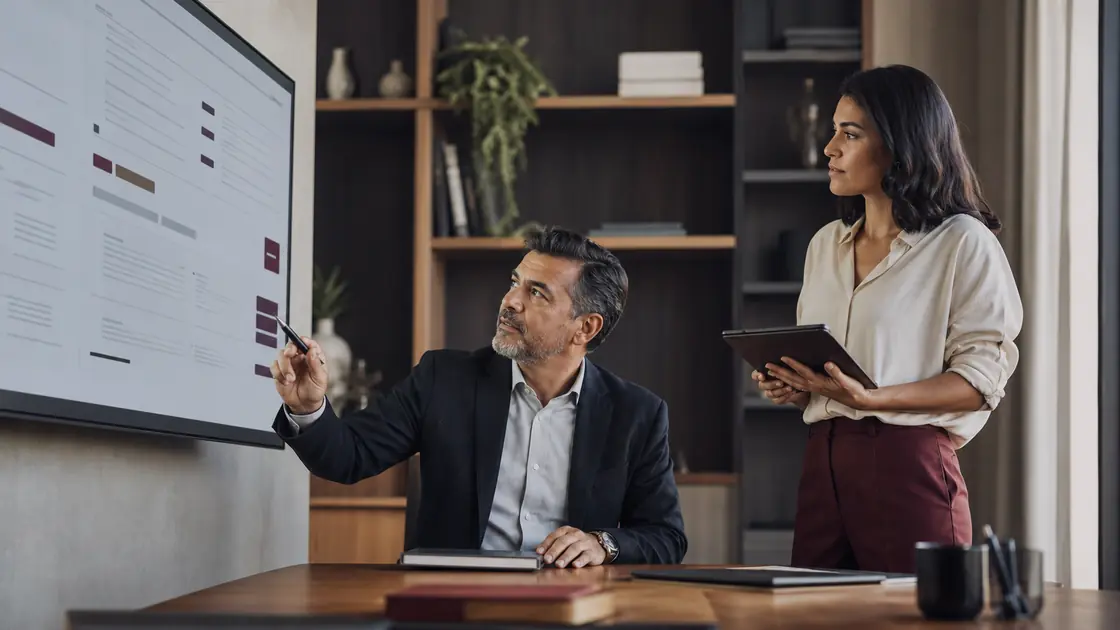 Dos personas de un equipo de talento revisando en una pantalla el reporte de una entrevista; una de ellas señala una valoración con la pluma.